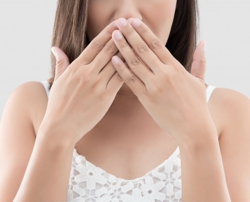 woman covering her mouth to hide her stained teeth