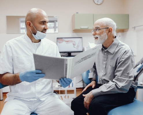 Older man siting with his dentist discussing treatment