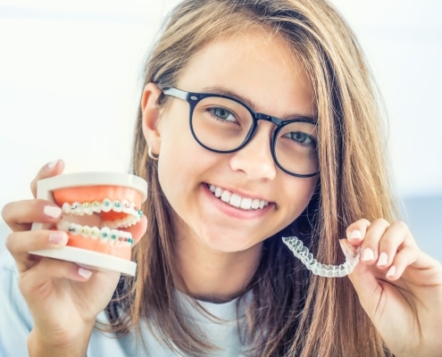 Dental invisible braces or silicone trainer in the hands of a young smiling girl. Orthodontic concept - Invisalign.