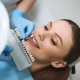 cheerful-young-lady-is-lying-dental-chair-choosing-veeners-colour-with-doctor-help